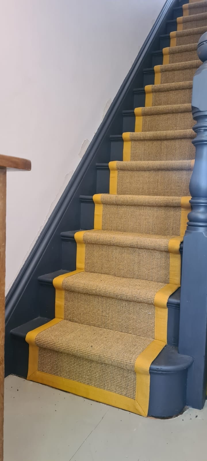 Turmeric sisal stair runner with taped edge against blue painted staircase